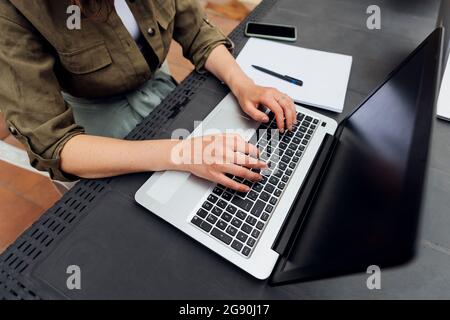 Female freelancer using laptop while sitting at desk Stock Photo