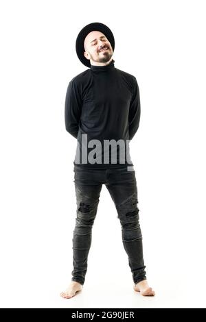 Relaxed happy unconventional style man smiling in black turtleneck with hat barefoot. Full length portrait isolated on white background Stock Photo