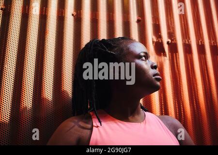 Young woman looking away in front of corrugated brown wall Stock Photo
