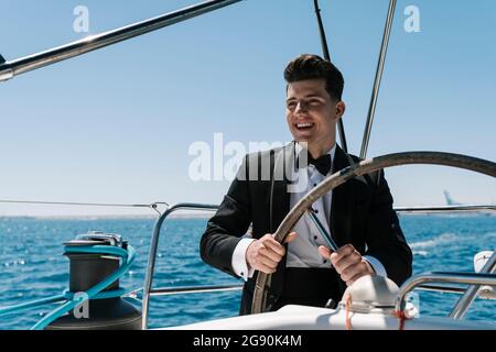 Smiling young man sailing yacht in summer Stock Photo