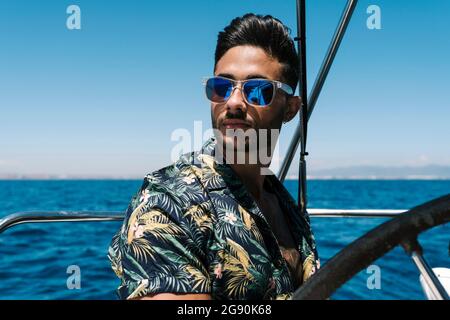 handsome young man wearing sunglasses sitting with bottles of red