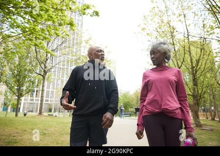 Man talking to senior woman walking in public park Stock Photo