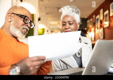 Businessman discussing over documents with female colleague in restaurant Stock Photo