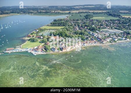 Aerial view along the historic waterfront of Bosham Village on an estuary in West Sussex with the Holy Trinity Church in the centre of the village. Stock Photo