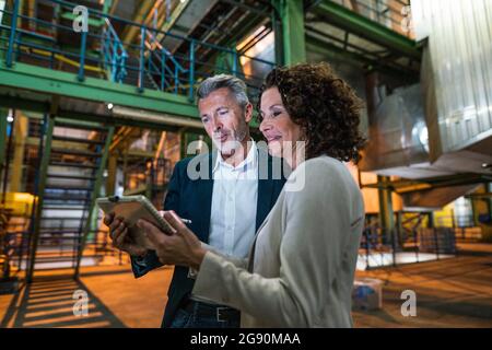 Professional team using digital tablet while standing in industry Stock Photo