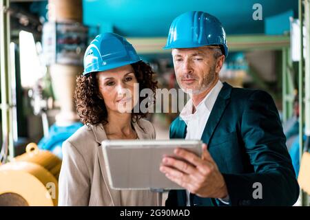 Expertise team with hardhat using digital tablet in industry Stock Photo