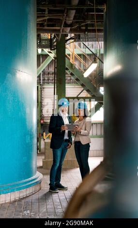 Expertise team with hardhat using digital tablet in workshop Stock Photo