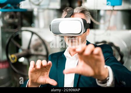 Businessman gesturing while using virtual reality headset at workshop Stock Photo