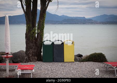 three different garbage cans to separate garbage stand on the shore of Garda Lake Stock Photo