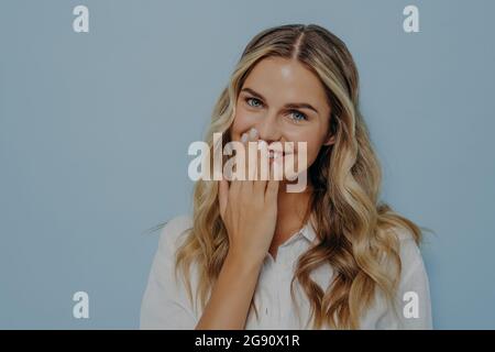 Blonde woman being flattered covering her mouth with hand Stock Photo