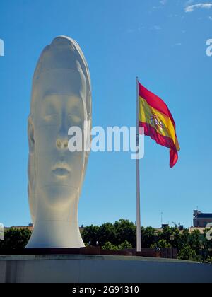 Madrid, Spain - July 12, 2021. Julia, a sculpture by Jaume Plensa with the Spanish flag in the background. Plaza de Colon square. Madrid, Spain. Stock Photo