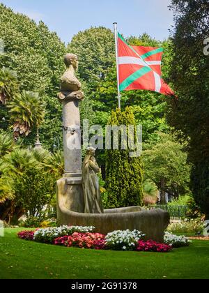 Monument to Jose Maria Usandizaga at Plaza de Guipuzcoa Square wiyh the Basque Country flag in the background. San Sebastian, Gipuzkoa, Spain. Stock Photo