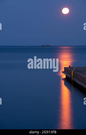 Helsinki / Finland - JULY 22, 2021: A detail of a industrial pier with full blood moon in the background. Stock Photo