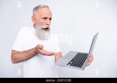 Portrait of attractive outraged worried man using laptop reading report isolated over light grey color background Stock Photo