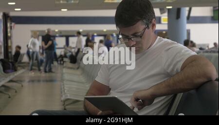 Man Passing Time before Departure with Tablet Stock Photo