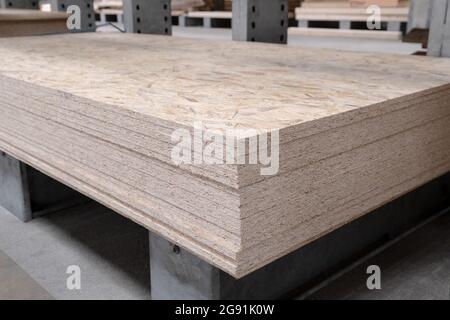 The stack of OSB sheets are stacked in a hardware store on a pallet. plywood with fragments of compressed sawdust, prepared for construction. Selectiv Stock Photo