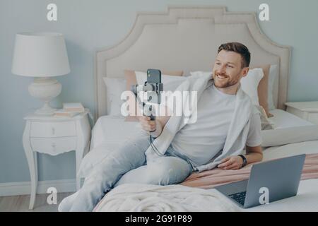 Young man lying on bed while video chatting using phone Stock Photo