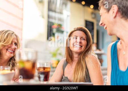 Three middle-aged adult women in a cafe having drinks and having fun Stock Photo