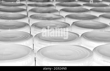 White plastic containers with lids lined up in rows with shadows and textures, low angle view. Stock Photo