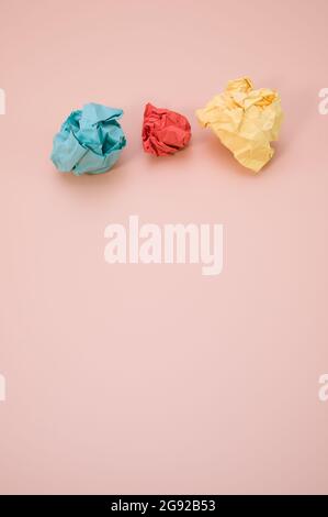 Vertical shot of aligned crumpled colored paper isolated on a pink background with copyspace Stock Photo