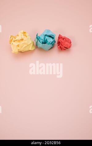 Vertical shot of aligned crumpled colored paper isolated on a pink background with copyspace Stock Photo