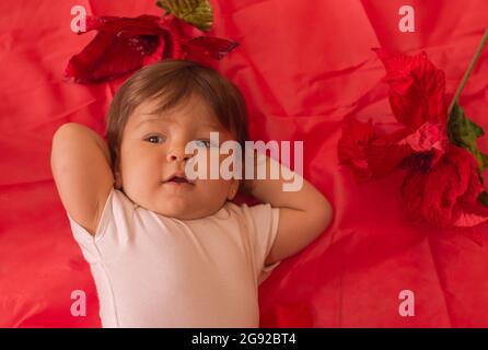 Little one year girl baby Resting in a red background with flowers  Stock Photo