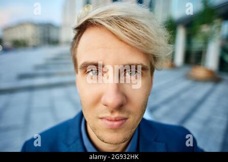 Young blonde man with serious look close up outside. Stock Photo