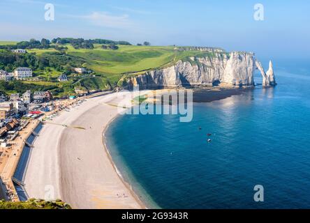 High angle view of the seafront and pebble beach of Etretat in Normandy with the Needle and the arch of the Aval cliff in the distance on a sunny day. Stock Photo