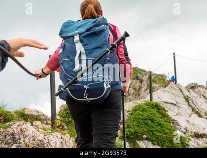 Female hikers using metal rope traversing the Kozya Stena Peak or Chamois Wall on the long distance trail E3 Path, Troyan Mountain, Bulgaria Stock Photo