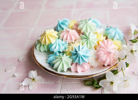 Small colorful meringues in the  ceramic plate on pink tile background Stock Photo
