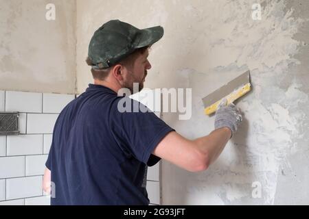 Caucasian man put plaster patching up the cracks on the wall. Stock Photo