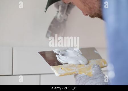 Caucasian man put plaster patching up the cracks on the wall. Stock Photo