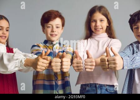 Studio group shot of happy satisfied little children giving thumbs up all together Stock Photo
