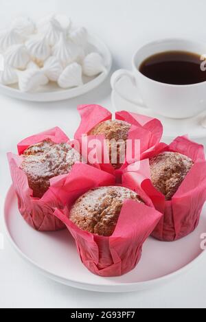 Muffins, marshmallows and black coffee on a white table. Stock Photo