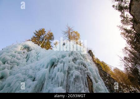 Female ice climber going down an ice waterfall, using a safety top rope. Stock Photo