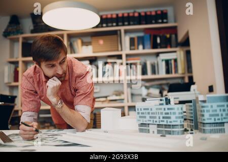 Thoughtful architect with blueprints and layout design project at office. Stock Photo