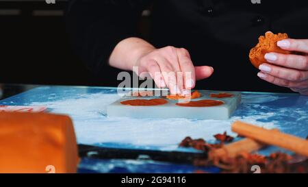 Close-up shot of woman's hands working on gingerbread cookies. In front there is pastry dough. Stock Photo