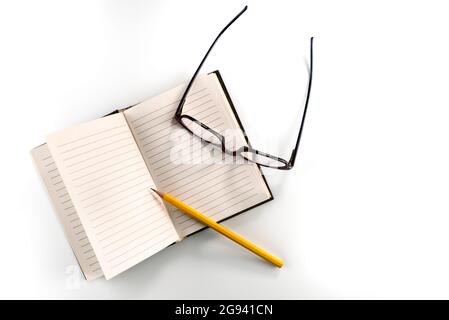 Vintage lined notebook with yellow pencil and glasses, isolated on white background, copy space Stock Photo