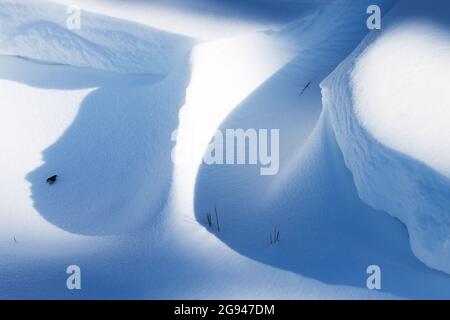 Snowdrifts with blue shadows during a sunny day on late winter in Europe. Stock Photo