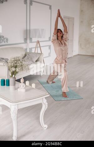 Young lady starting morning with yoga exercises in bedroom Stock Photo
