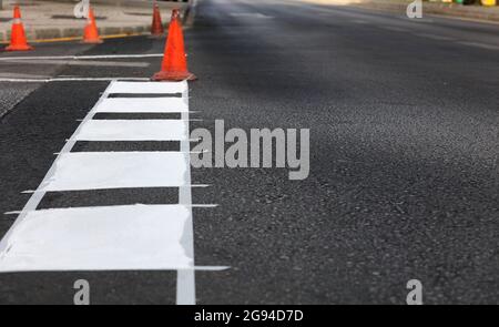 thermoplastic road marking tape, painting traffic lines and bike lanes on asphalt road surface, selectiva focus Stock Photo