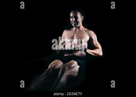 Strong man rowing on a machine. Stock Photo