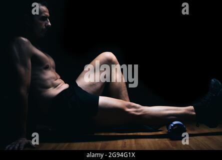 Man sitting on the floor doing stretching exercises Stock Photo