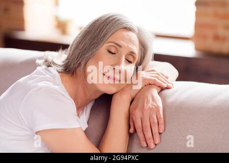 Portrait of attractive dreamy calm grey-haired woman granny sitting on divan resting free time at home house flat indoors Stock Photo