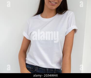 Tshirt mockup, front view of unrecognizable woman wearing white tshirt. Copy space on empty area on her t-shirt for design or inscription. Fashion lifestyle mock up of white tshirt. T-shirt template. Stock Photo