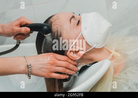Hairdresser during the world quarantine, washing the head in a beauty salon, a client in a mask. new Stock Photo
