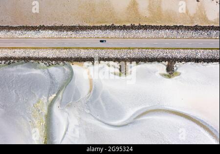 Creagorry, Benbecula,  Scotland, UK. 24 July  2021. A drone image which shows a car driving across the causeway which connects the Islands of Benbecula and South Uist at low tide in the Outer Hebrides, Scotland, UK.  Iain Masterton/Alamy Live news. Stock Photo