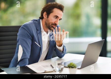 A man sitting at a table using a laptop Stock Photo