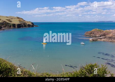 A yacht in the bay of clear blue water at Hope Cove, South Devon, UK on a sunny spring day. Stock Photo