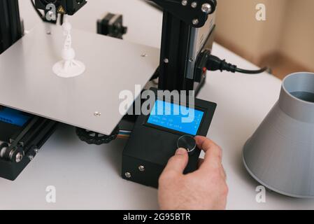 Young engineer in the lab adjusting a 3D printer's components Stock Photo